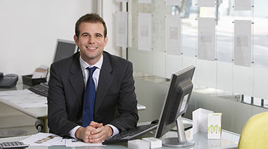 a similing young man in business suit sitting in an office